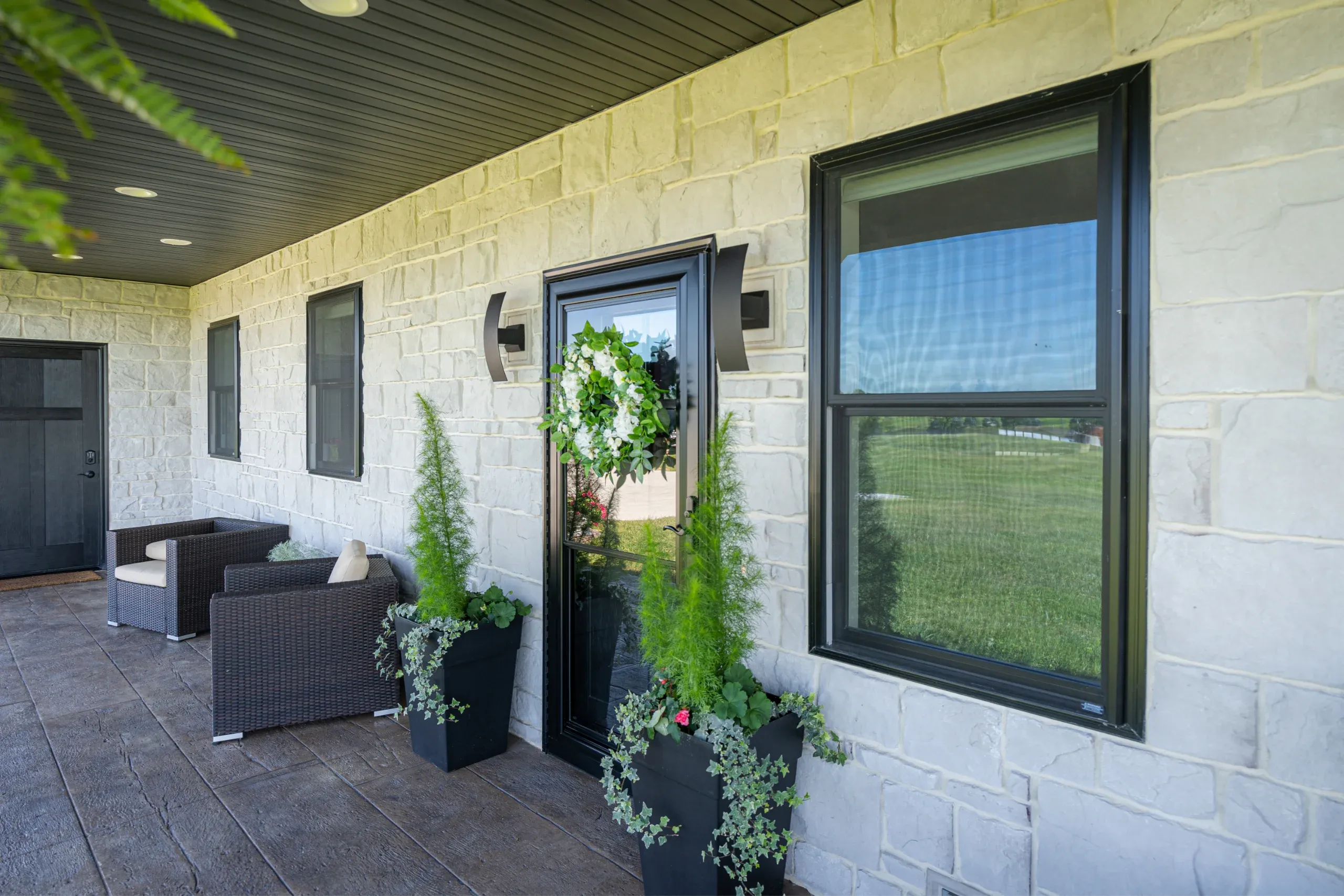 Black replacement windows on a white stone home exterior