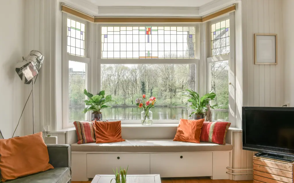 Cozy living room interior featuring a large bow window with a built-in window seat overlooking a scenic lake in Toledo, Ohio.