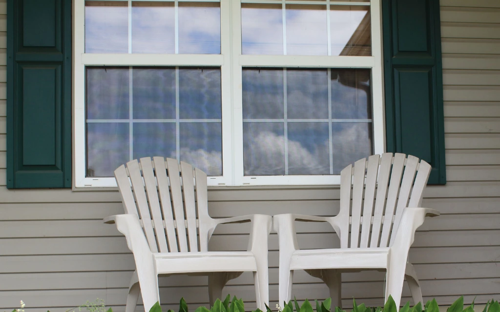 Exterior view of a grid-pane sliding window installation paired with dark green shutters on siding in Toledo, Ohio.