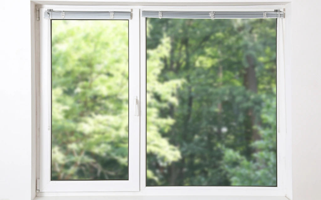 Interior view of a modern white vinyl double-slider window with mini-blinds installed in Toledo, Ohio