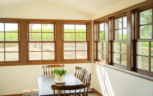 Wood-framed double hung windows in a bright dining room overlooking the outdoor landscape.