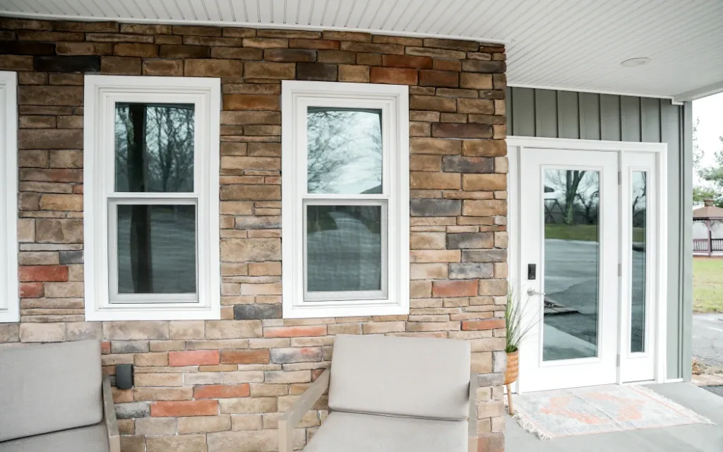 White replacement windows and entry door on a brick exterior