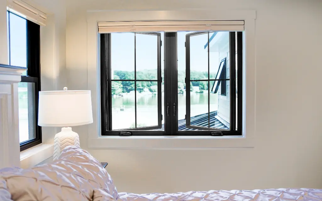 Modern black casement replacement windows opened inward in a bright bedroom, providing natural ventilation and scenic outdoor views in a Toledo, Ohio home.